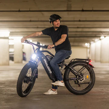 Man riding a black PHILODO Jumbo Dual Motor Electric Bike in an underground parking garage