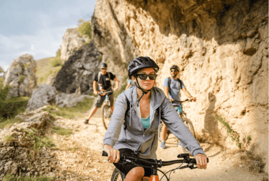 Electric bike group riding on rocky mountain trail, front view with helmets and sunglasses