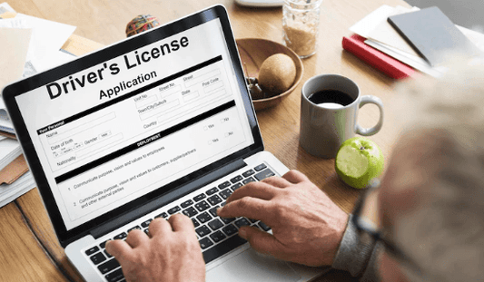 Person filling out driver’s license application form online on a laptop at a desk