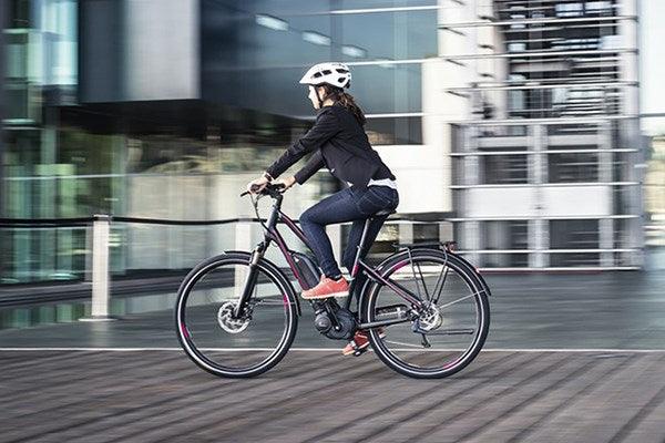 Woman commuting on a modern electric bike outside office, Pogo Cycles e-bike store