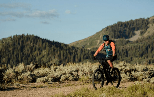 Cyclist riding an electric bike on a scenic trail with mountains, Pogo Cycles outdoor adventure