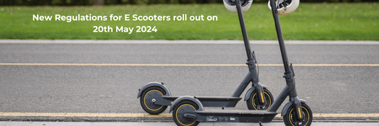 Two black electric scooters side view parked on a city road with green grass background