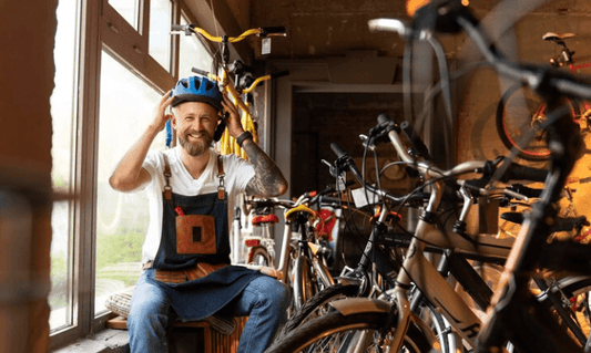 Smiling man in bike shop with electric bikes, wearing helmet, Pogo Cycles e-bike store