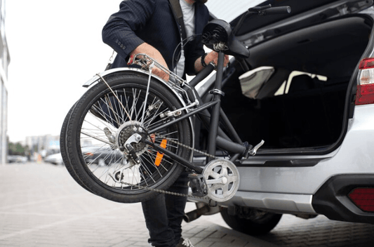 Man loading folding electric bike into car trunk, showcasing compact e-bike for commuting from Pogo Cycles